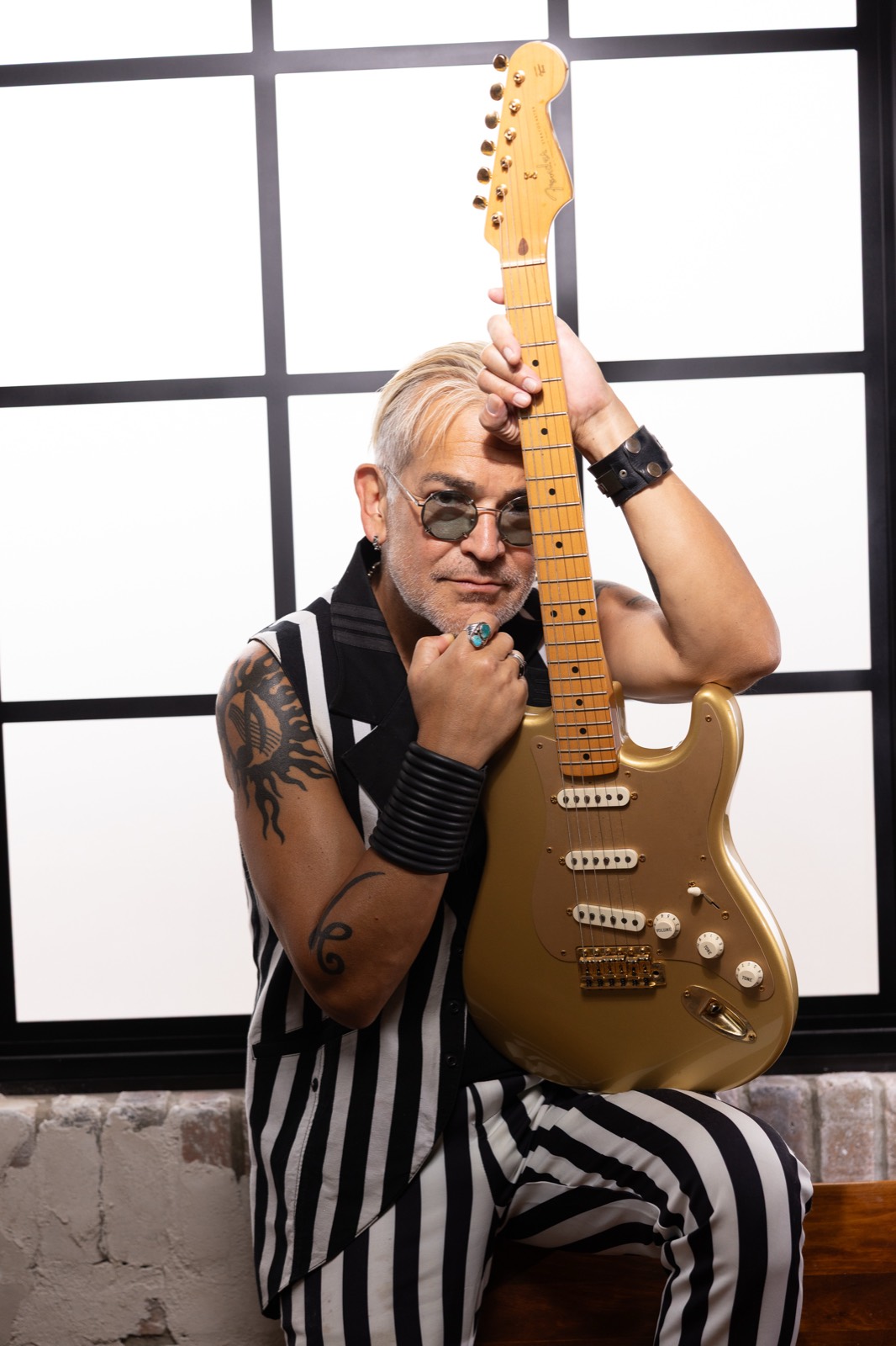 Rik Avalos holding a gold Stratocaster, studio portrait