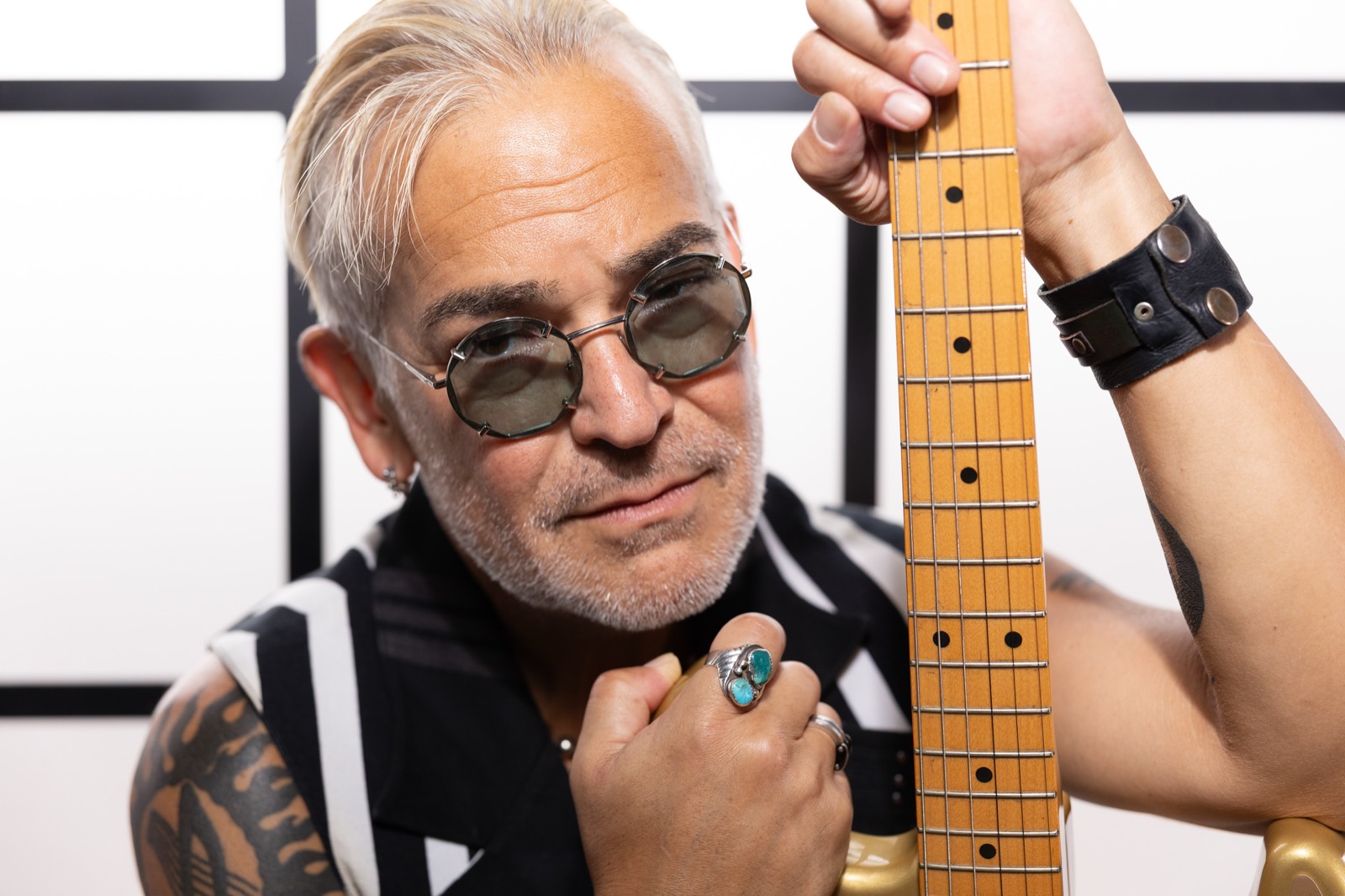 Rik Avalos with a gold electric guitar, studio portrait